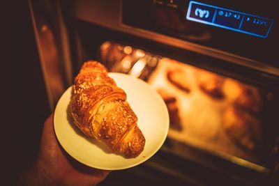 Cropped image of hand putting croissant in oven