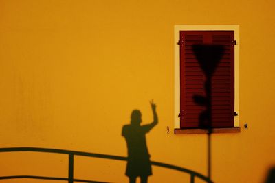 Silhouette man standing against yellow wall