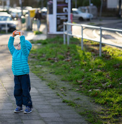 Full length of boy holding toy on footpath