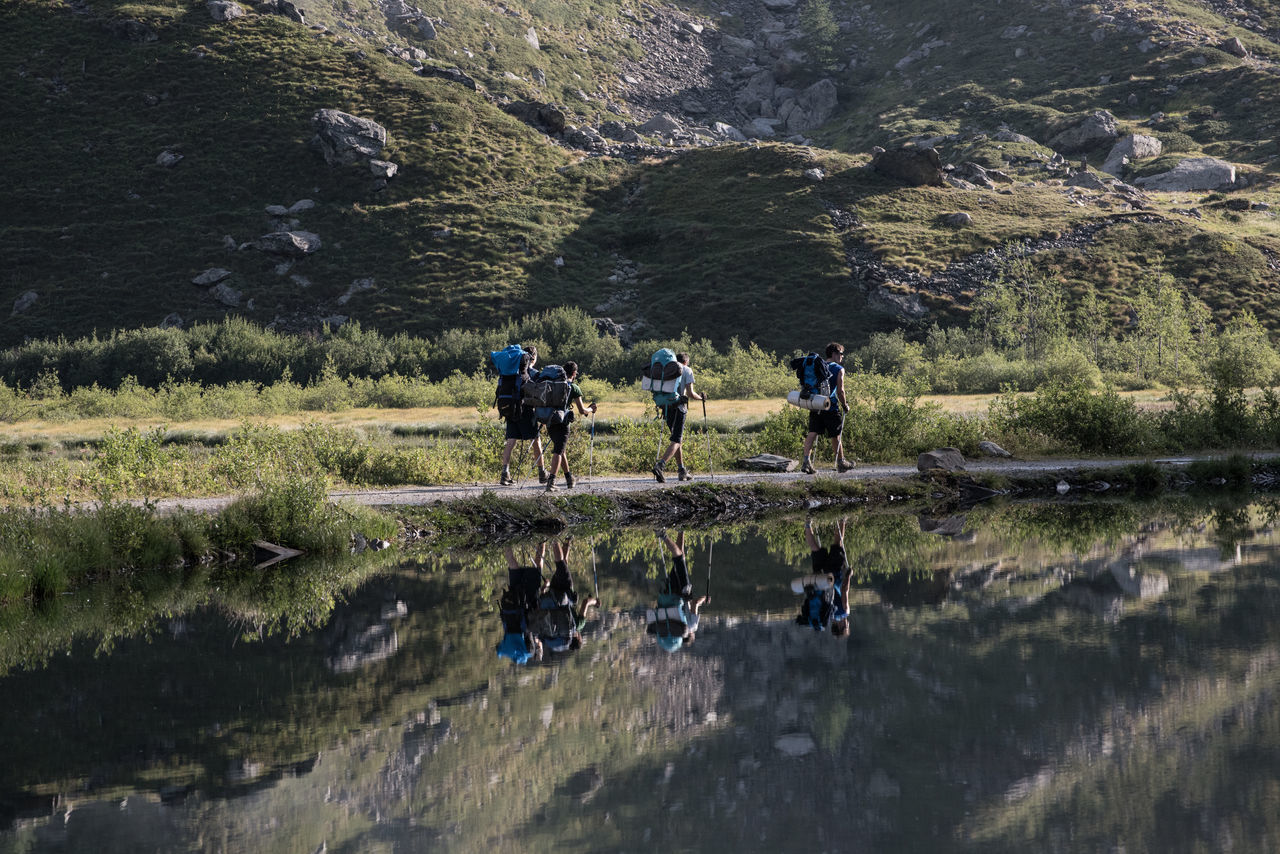 PEOPLE WALKING ON WATER AGAINST MOUNTAIN