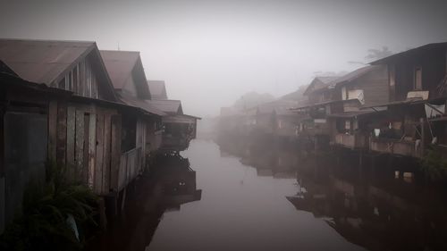 Buildings by river in city against sky