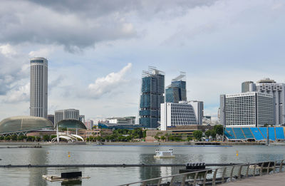 Modern buildings by river against sky in city