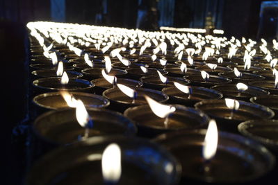 Row of burning candles in illuminated building