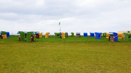 Hooded chairs on field against sky