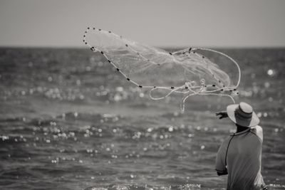 Rear view of woman wearing hat on sea shore against sky