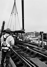 Rear view of man working at construction site against sky