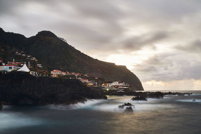 Scenic view of sea by buildings against sky