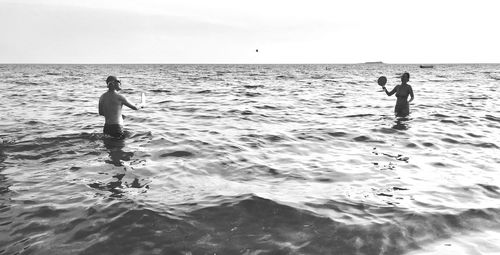 People playing tennis in sea against sky