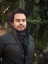 Portrait of young man standing against plants