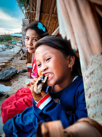 Girl eating food while sitting with sister outdoors