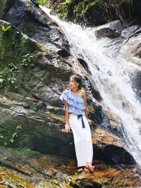 Full length of woman standing against waterfall