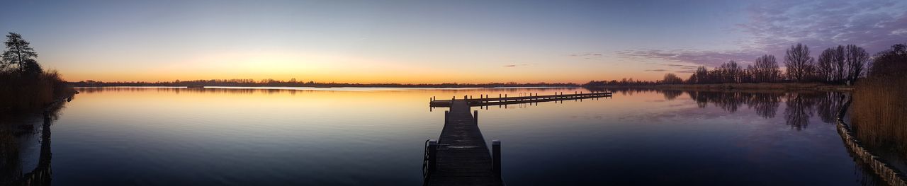 Pier on lake against sky during sunset