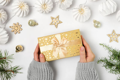 Woman hands holding gift box with gold colored ribbon and bow. caucasian female hands hold christmas