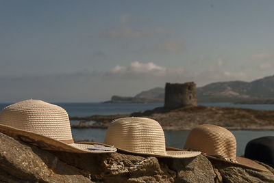 Close-up of hat on rocks by sea against sky