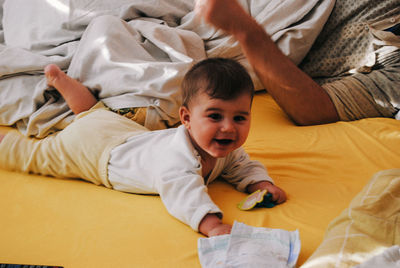 High angle view of baby lying on bed with father at home
