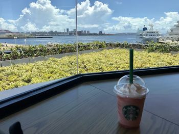 Drink on table by sea against sky