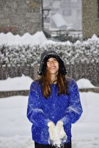 Smiling young woman standing on snow