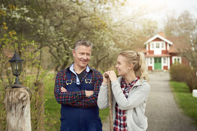 Confident farmer looking at smiling daughter while standing on footpath