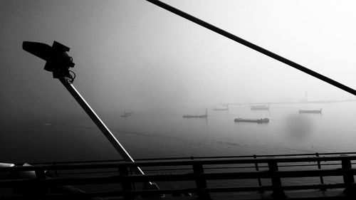 Illuminated railing by sea against sky