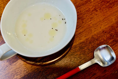Top view of cream soup with pepper and spoon on a wooden background