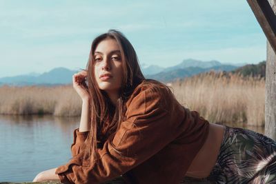 Portrait of young woman posing against lake