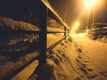 Snow on illuminated road against sky at night during winter