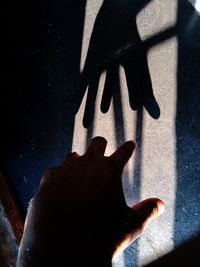 High angle view of human hand touching shadow