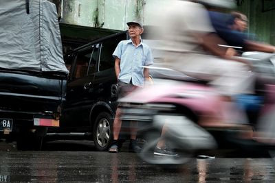 Man standing on road by car