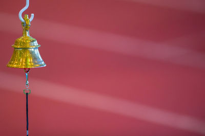 Low angle view of illuminated electric lamp against wall