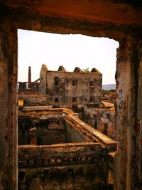 Old ruin building against sky seen through window