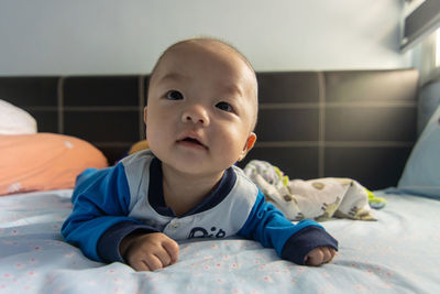 Portrait of cute baby lying on bed at home