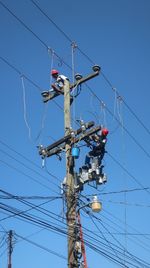 Low angle view of power lines against clear blue sky