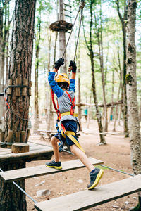 Full length of man jumping on tree trunk in forest