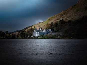 Lake by buildings against sky at night