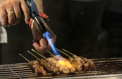 Close-up of man preparing food on barbecue grill