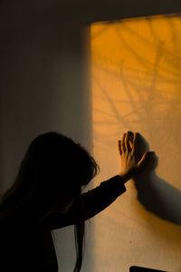 Shadow of woman sitting on wall at home