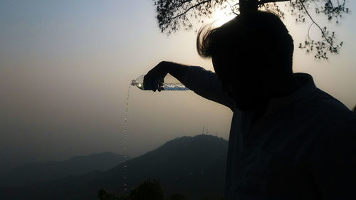 Rear view of silhouette man against lake against sky