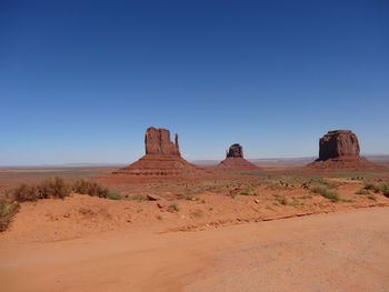 Scenic view of arid landscape against clear blue sky