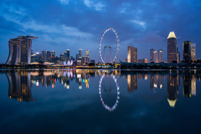 Reflection of buildings and ferris wheel in river at night