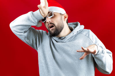 Portrait of young man standing against red background