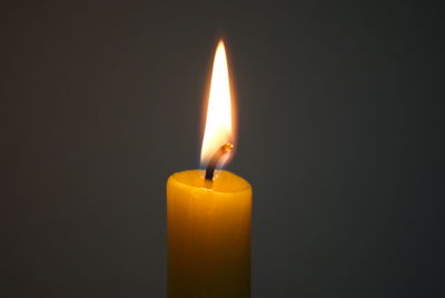 Close-up of burning candle against black background