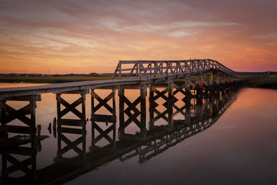 Bridge over river against sky during sunset