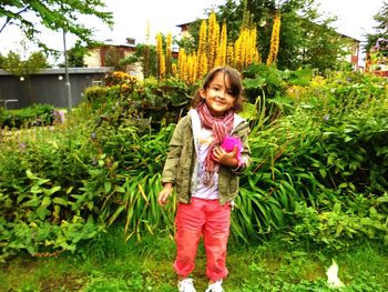 Portrait of happy girl standing against plants