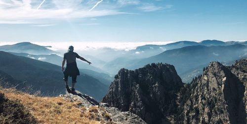 Rear view of man standing on mountain against sky