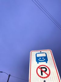 Low angle view of road sign against clear blue sky