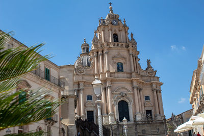 A palm tree looks out towards the cathedral of ragusa ibla