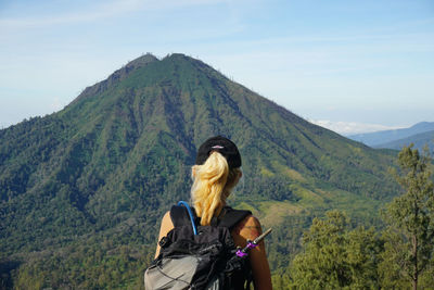 Rear view of woman looking at mountain against sky