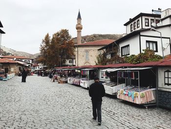 Rear view of people walking on street amidst buildings in city