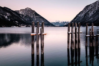 Wooden posts in lake against sky during sunset