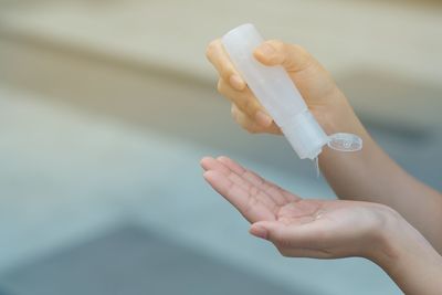 Close-up of woman hand holding bottle against blurred background